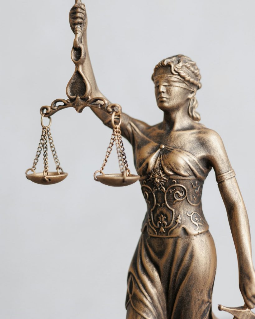 close-up themis is goddess of justice statuette on dark background. symbol of law with scales