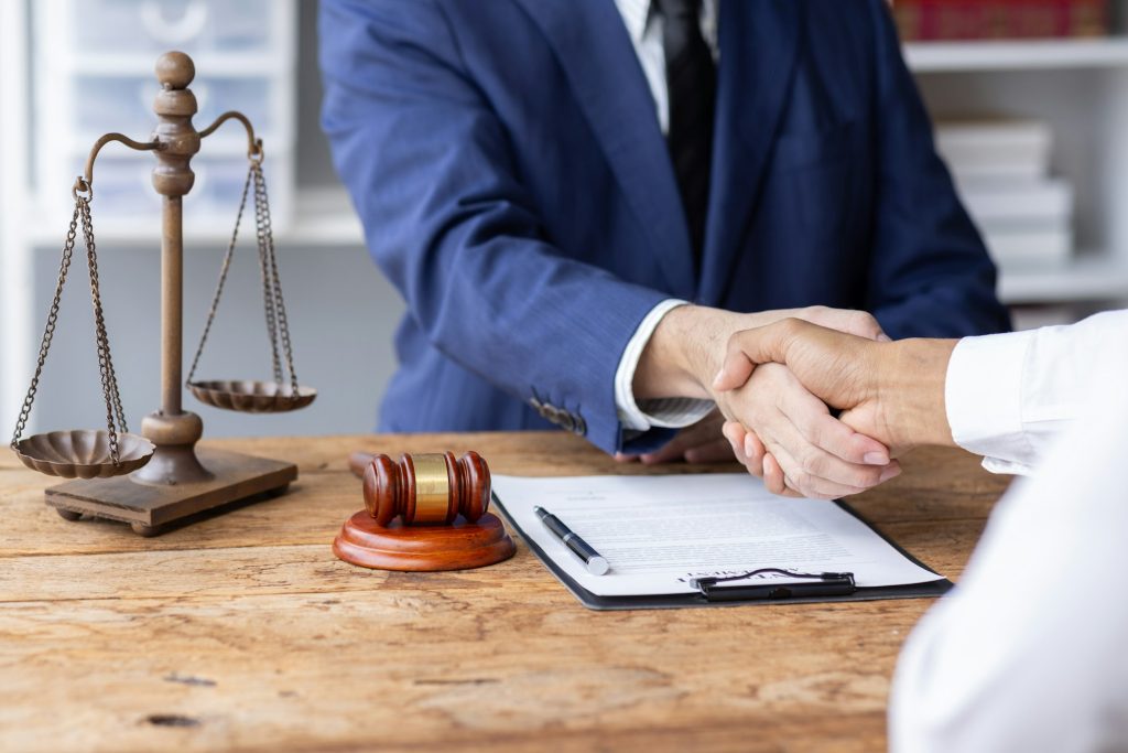Businessman Shaking Hands In Front Of Mallet, justice and law concept. male lawyer working in office